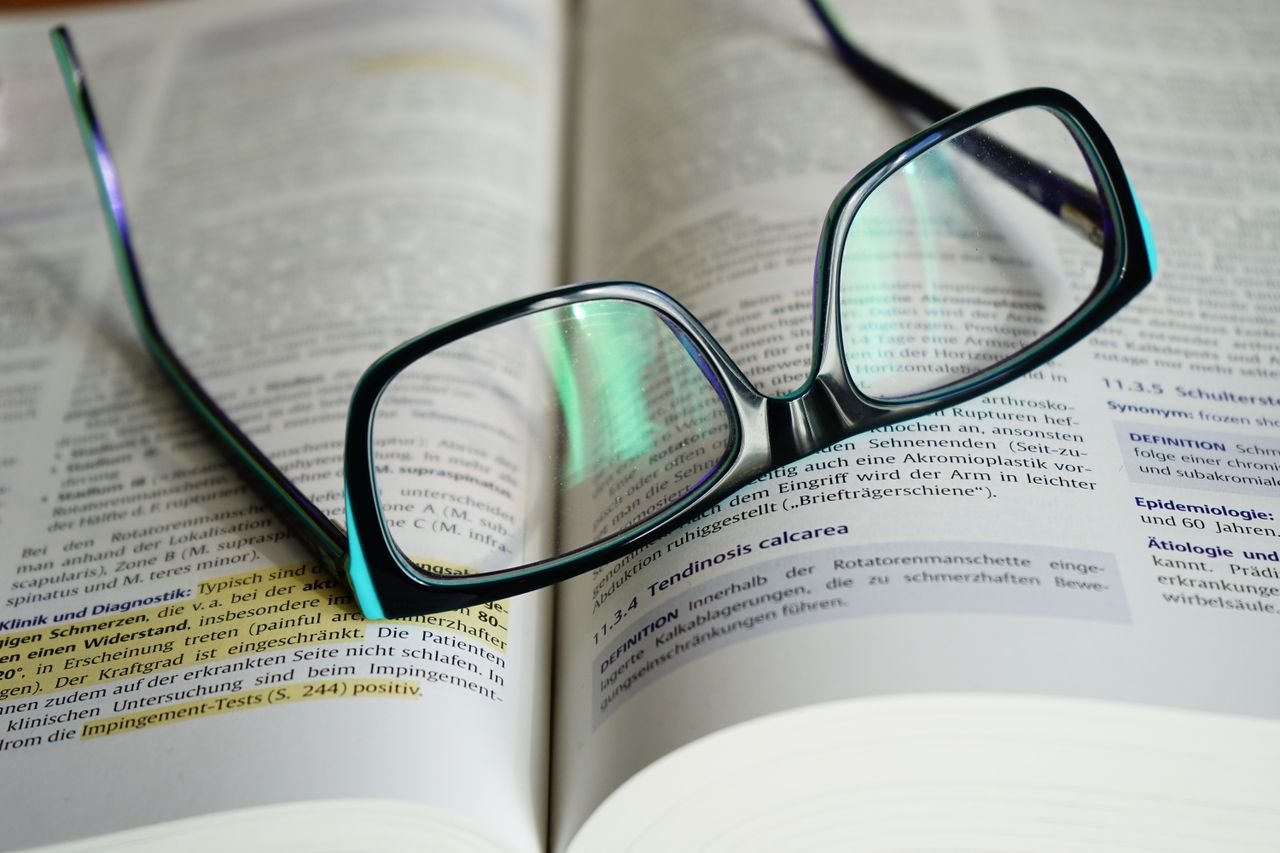 about-us-02 Reading glasses resting on an open book, symbolizing knowledge and learning.
