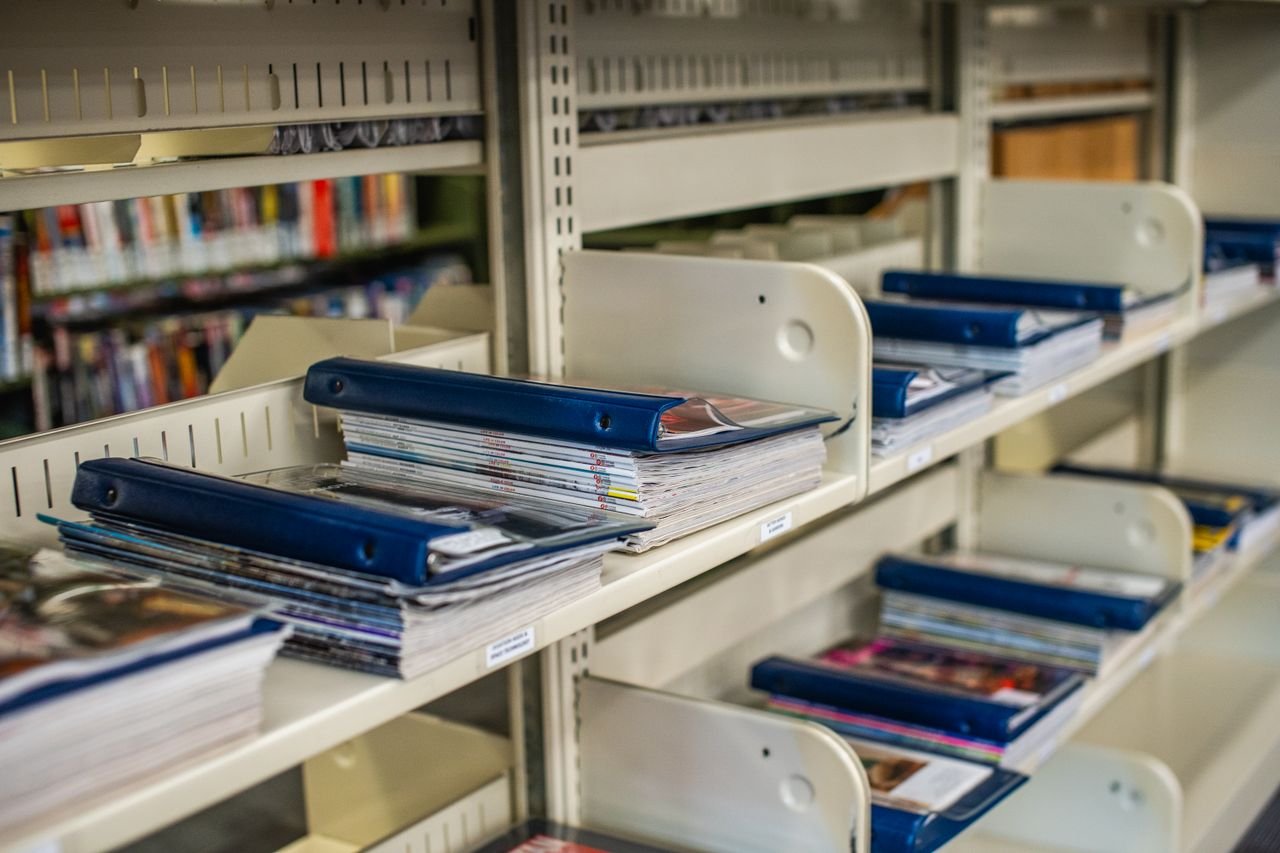 services-02 Neatly arranged binders and magazines on library shelves showcasing organization.
